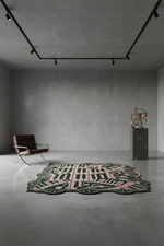 Modern room with a patterned rug, chair, and sculpture on a concrete floor.