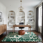 A styled home office interior featuring a large green and cream patterned area rug under a wooden desk and black office chair. The room has white walls with built-in arched bookshelves, a gold geometric pendant light, and dark gray curtains.