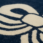 Close-up of a textured rug with a cream-colored abstract pattern on a dark navy blue background.