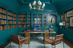 Stylish office with teal blue rug, walls, bookshelves, and a wooden desk.
