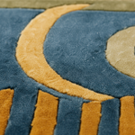 Close-up of a plush textured rug featuring a blue base with mustard yellow crescent moon and vertical stripe patterns.