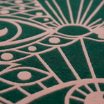Close-up of a textured felt surface with a repeating geometric sun and moon pattern in dark green and pale pink.