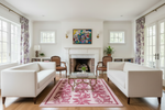 Living room with white sofas, a pink rug, and decorative elements.