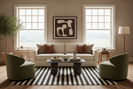 Modern living room with a white sofa, green chairs, black and white rug, and abstract art on the wall.