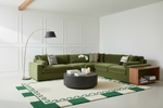 Modern living room with a green sectional sofa, green rug, coffee table, and decorative items.