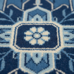 Close-up of a textured woven rug with a geometric medallion pattern in navy blue, light blue, and off-white.
