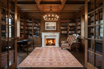 Cozy library with wooden bookshelves, pink rug, fireplace, and armchair.