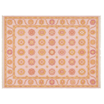 A rectangular area rug with a light pink background and an intricate geometric and floral pattern in orange, yellow, and coral, finished with white fringe on the short ends.