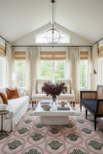 Living room with white sofa, pink and green floral rug, coffee table, and decorative elements.