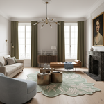 A styled living room interior with olive green curtains, a light beige sofa, a tan leather chaise, a pale green and cream patterned area rug, a sculptural brass coffee table, and a large portrait painting above a dark marble fireplace.