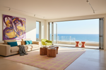 Modern living room with ocean view, colorful rug, and furniture.
