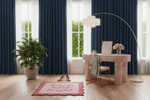Modern home office with blue curtains, scallop pink rug, desk, chair, and decor items.