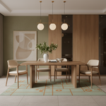 A modern dining room setup featuring a rectangular wooden dining table surrounded by four light wood armchairs with cream cushions, set on a patterned mint green and beige rug. Above, a three-light linear pendant lamp hangs over the table.