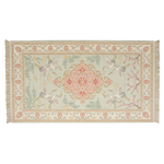 A rectangular woven rug with fringe on the short ends, featuring a pale sage green field, a central pink and gold medallion, two white cranes with blue accents, and floral motifs in the border.