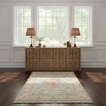 A traditional-style area rug with a floral medallion and fringe, styled on a dark wood floor in front of a carved wooden sideboard with two lit table lamps.