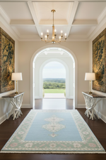 Luxurious hallway with a light blue rug, white walls, and a large window.