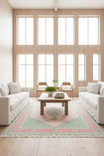 A styled living room with two white sofas facing a wooden coffee table on a large rectangular area rug. The rug has a cream center, a dusty pink border, and a pale mint green geometric pattern.