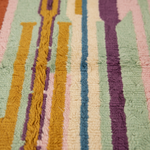 Close-up of a textured rug with vertical stripes in pastel green, cream, pink, blue, purple, and mustard yellow.