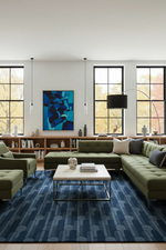 Modern living room with a sectional sofa, coffee table, and decorative blue contemporary rug.