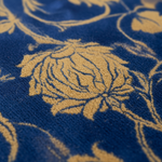 Close-up of a textured rug featuring a deep blue base with a raised, golden-yellow floral pattern.