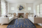 Living room with white sofas, a blue and gold rug, and a fireplace.