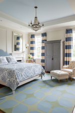 Luxurious bedroom with striped curtains, a chandelier, and patterned rug.