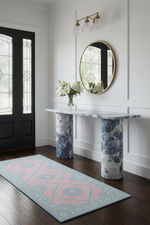 Decorative rug and console table with floral design in a room with a black door and white walls.