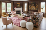 Living room with floral red rug, sofa, armchairs, and a fireplace.