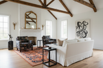 Living room with white walls, orange rug, wooden beams, and a white sofa.