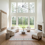 Modern living room with large windows, white furniture, pink shaggy rug, and a fireplace.