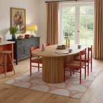 Dining room with wooden table and red chairs on a patterned rug.