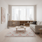 A modern, minimalist living room featuring a light beige sofa, a matching patterned area rug, a light wood coffee table, and a built-in wooden desk and shelving unit under a large window.