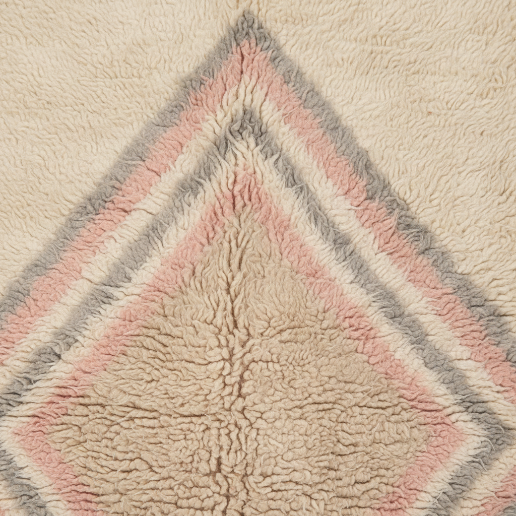 Close-up of a textured sherpa or fleece rug with a geometric diamond pattern in cream, dusty pink, and light gray.