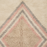 Close-up of a textured sherpa or fleece rug with a geometric diamond pattern in cream, dusty pink, and light gray.