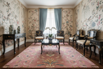 Decorative living room with floral wallpaper, a pink rug, and classical furniture.