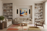 Modern living room with beige sofa, rug, bookshelves, and abstract art