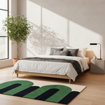 Modern bedroom with a bed, contemporary green rug, and large windows.