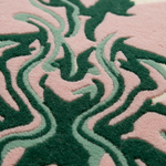 A close-up of a textured rug featuring a wavy, abstract pattern in dark forest green, light sage green, and soft pink.