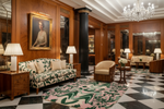 Luxurious interior of a hotel lobby with wooden walls, floral-patterned rug, and chandelier.