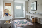 Modern bathroom with a freestanding bathtub, shower, and decorative pink rug.