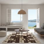A modern living room interior with a geometric area rug in brown and beige tones, a round coffee table, a bench, a gray sofa, and large windows opening to a blue sea view.