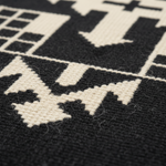 Close-up of a woven textile with a bold black and off-white geometric pattern, showing the texture of the fibers.