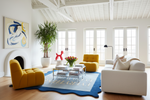 Modern living room with yellow chairs, white sofa, and decorative blue area rug.