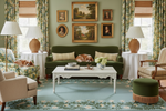 Living room with green sofa, floral blue rug, and decorative wall art.