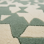 Close-up of a textured area rug with a geometric pattern of sage green and cream interlocking shapes.