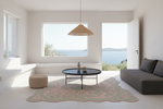 A modern living room with a large, organic-shaped pink and sage green patterned rug on a white floor. A round black coffee table sits on top of the rug, next to a dark gray sofa.