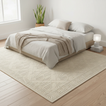 A large cream-colored area rug with an embossed geometric and leaf-like pattern, styled in a bright, modern bedroom under a low-profile platform bed with neutral bedding.