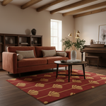 A styled living room scene featuring a rust-orange upholstered sofa with two beige throw pillows, set on a red area rug with a gold fan pattern. The room has warm beige walls, wooden ceiling beams, a dark wood bookshelf, and a dark wood coffee table.