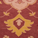 Close-up of a patterned rug with a deep red background and a yellow and light pink ornamental medallion design.