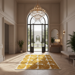 A large rectangular area rug with a bold yellow and white abstract floral pattern is displayed in a grand, elegant hallway with herringbone wood floors, a crystal chandelier, and arched black glass doors.